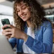     Femme souriante utilisant son téléphone et son ordinateur portable.