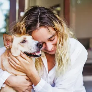 Une femme étreint d'affection son chien de couleur claire à l'extérieur.
