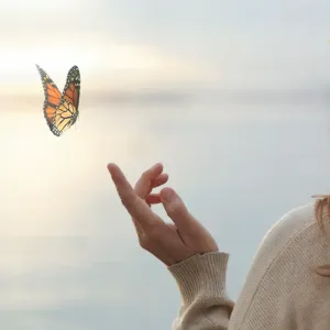Papillon s'envolant de la main tendue d'une personne, fond flou.