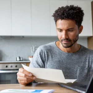 Un homme utilise un ordinateur portable dans une cuisine moderne, entouré d'ustensiles de cuisine.
