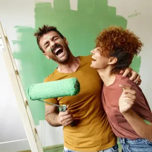 Un couple joyeux et éclaboussé de peinture verte fait une pause amusante pendant qu'ils rénovent leur intérieur.