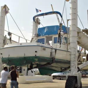 Bateau de plaisance blanc soulevé par un chariot élévateur de mise à l'eau dans un port de plaisance.