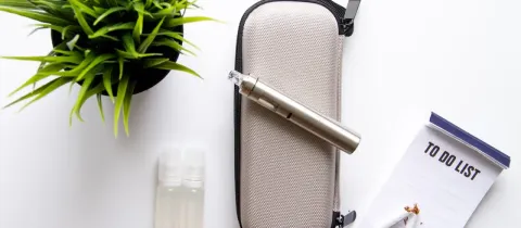Une cigarette électronique est posée sur une coque de protection, des recharges pour la cigarette électronique se trouve à gauuche de l'étui de protection. Une cigarette cassée est sur une liste de choses à faire.