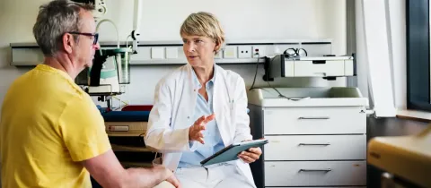 Une femme médecin explique des choses à un homme plus âgé dans une salle d'examen.