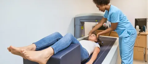 Technicienne préparant une femme pour un examen de densité osseuse sur un appareil de Densitométrie.