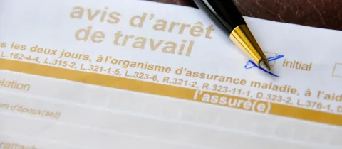 Gros plan d'un formulaire d'avis d'arrêt de travail avec un stylo.