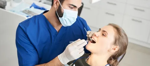Un dentiste masqué effectue un examen dentaire sur une patiente.