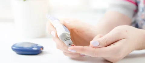 Gros plan sur une femme utilisant un lecteur de glycémie pour tester son sang.