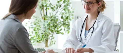Une femme médecin souriante et une patiente discutent lors d'une consultation au cabinet.