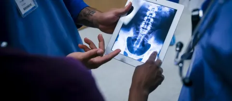 Un médecin tenant une tablette affichant une image radiographique.