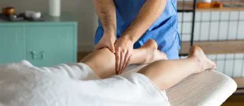 Un massothérapeute donne un massage des jambes à un patient allongé sur une table.
