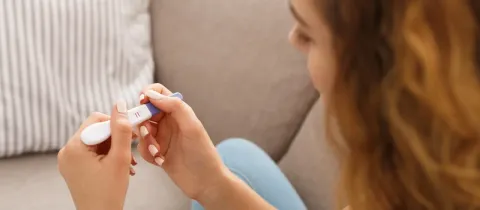 Gros plan sur une femme observant le résultat positif d'un test de grossesse à la maison.