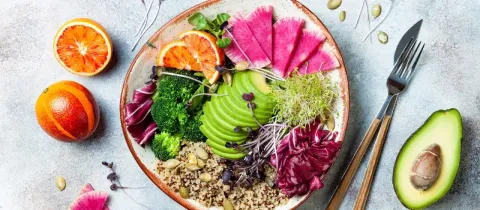 Un bol coloré rempli d'une salade végétalienne avec avocat, quinoa et légumes frais, prêt à être dégusté.