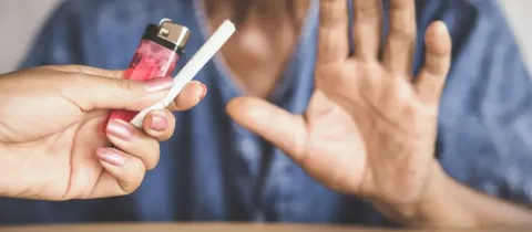 Une personne refuse une cigarette tendue par une autre main, faisant un signe d'arrêt.