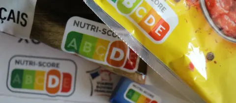 Gros plan sur plusieurs emballages de produits alimentaires affichant clairement le logo Nutri-Score avec différentes évaluations.