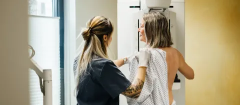 Une technicienne médicale aide une femme lors d'une mammographie, un examen de dépistage du cancer du sein.