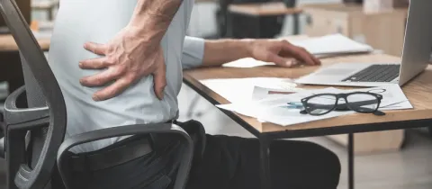 Homme au bureau souffrant de mal de dos, se tenant le flanc.
