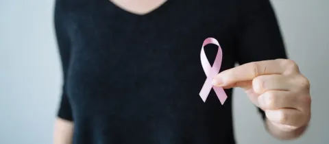 Main tenant un ruban rose, symbole de la lutte contre le cancer du sein.