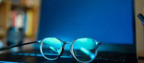 Lunettes anti-lumière bleue posées sur un ordinateur portable allumé.