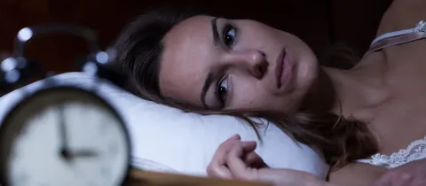 Femme allongée, fixant l'alarme, souffrant d'insomnie.