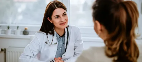 Médecin souriante discutant avec une patiente lors d'une consultation.