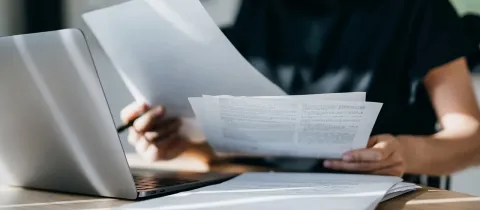 Femme lisant des documents sur un ordinateur portable à son bureau.