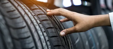 Une main touche un pneu neuf, montrant les sculptures de la bande de roulement.
