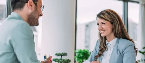 Un homme remet des clés de voiture à un autre homme souriant, à côté d'un véhicule.