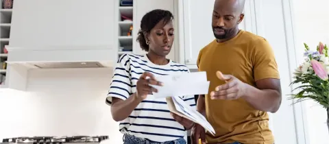 Dans une cuisine, un couple consulte des documents envoyés par courrier.