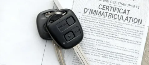 Une clé de voiture noire est posée sur un document officiel français : un certificat d'immatriculation.