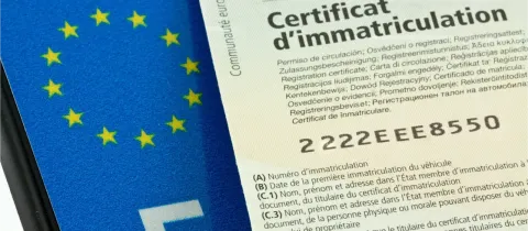Gros plan sur un certificat d'immatriculation européen français et une plaque d'immatriculation française.