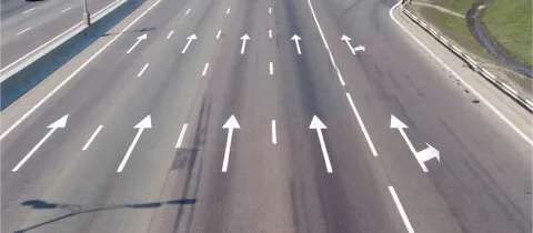 Vue aérienne d'une autoroute à plusieurs voies avec des flèches directionnelles peintes sur l'asphalte.