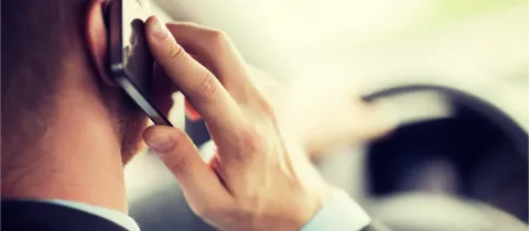 Vue arrière d'un homme en costume tenant un téléphone portable à son oreille en conduisant.