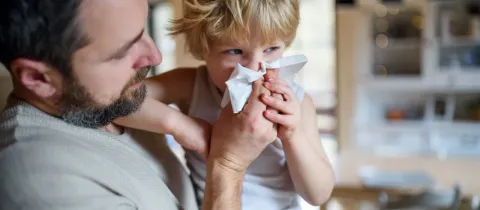 Père aidant son jeune fils à se moucher.