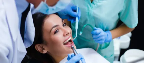 Un dentiste et son assistant soignent une patiente dans un cabinet.