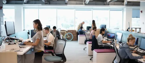 Espace de travail moderne et lumineux avec plusieurs employés travaillant sur ordinateurs.