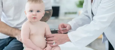 Un bébé reçoit une injection par un professionnel de santé.