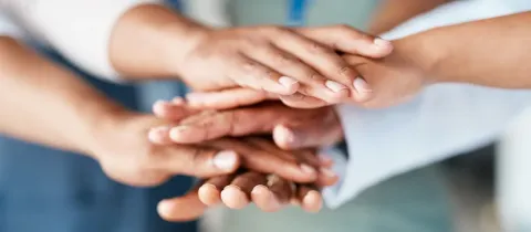 Mains empilées symbolisant la collaboration et le soutien mutuel.