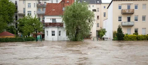 Inondation. L'eau boueuse a envahi la rue devant des bâtiments résidentiels. Scène de catastrophe naturelle urbaine.