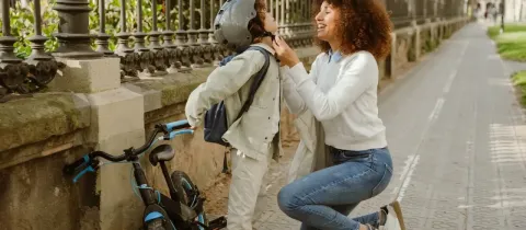 Une femme attache avec soin le casque de protection d'un jeune garçon avant une sortie à vélo en ville.