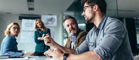 Quatre professionnels en réunion dans un bureau.