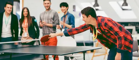 Un groupe de salariés joue au tennis de table, dans le cadre d'un atelier collaboratif en équipe.