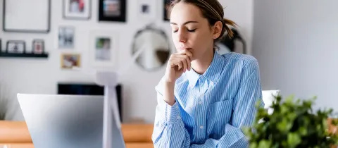 Une professionnelle travaillant à domicile sur son ordinateur prend une pause en fermant les yeux.