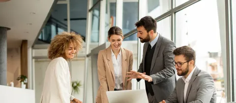 Équipe de salariés en train de parler dans un bureau devant un ordinateur.
