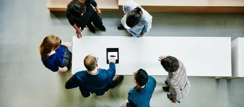 Groupe de collaborateurs réunis autour d'une table, vu du dessus.