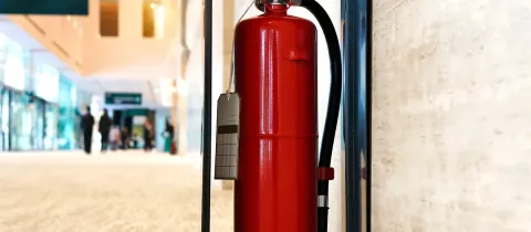Un extincteur rouge fixé au mur, prêt à être utilisé en cas d'incendie.