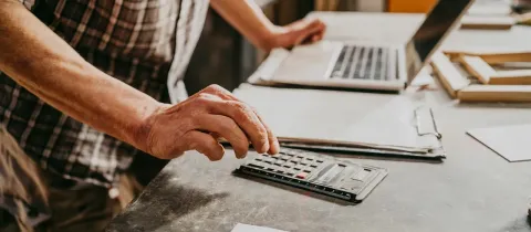 Personne utilisant une calculatrice et un ordinateur pour gérer une opération financière