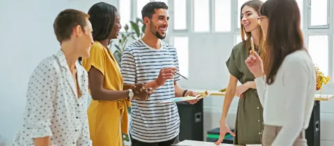 Collaborateurs de bureau discutant joyeusement autour d'une table de réunion avec un document.