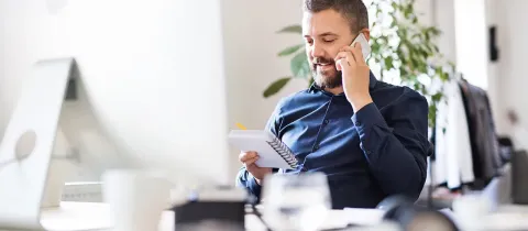 Homme au téléphone devant un écran d'ordinateur