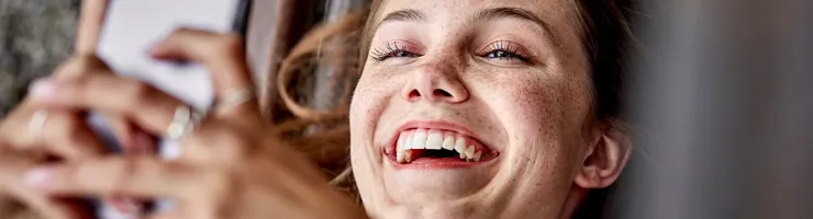 Femme regardant avec le sourire son téléphone